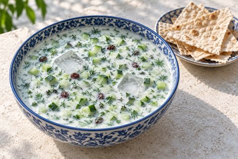 Cold cucumber-yogurt soup with herbs, raisins, ice and crisp lavash on the side; AI illustration.