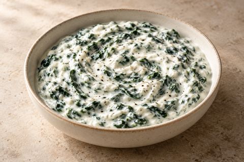 Spinach folded into thick white yogurt in a shallow bowl, AI-generated illustration.
