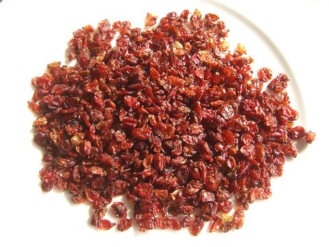 Red dried barberries on a white plate