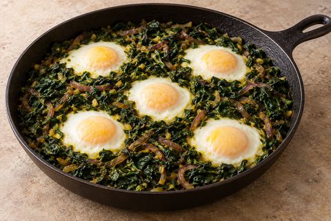 Five whole eggs with opaque whites nestled in cooked spinach and onion; AI illustration.