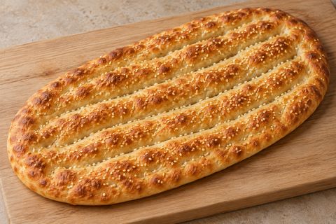 Golden oval Persian flatbread with long parallel grooves and sesame seeds; AI illustration.