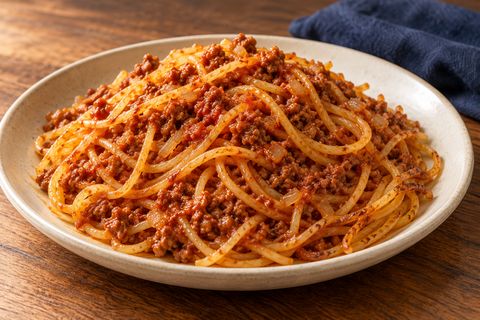 Tomato-beef spaghetti with a few lightly crisp strands on the side; AI illustration.