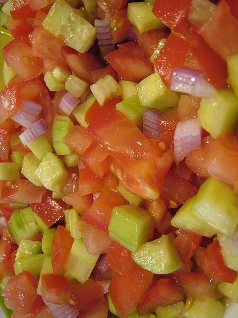 Close-up of diced tomatoes, pale-green cucumber and purple-red onion in a mixed salad