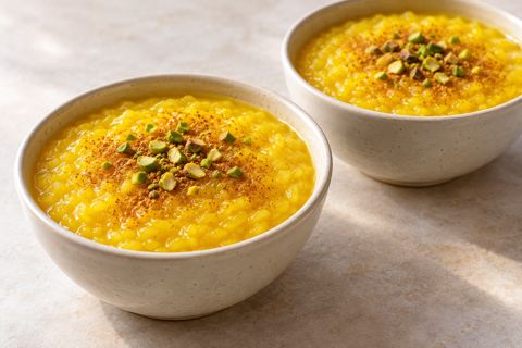 Golden saffron rice pudding topped with cinnamon and chopped pistachios; AI illustration.