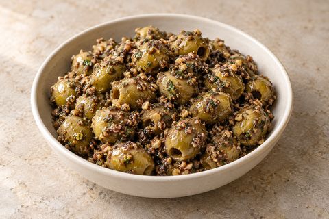 Green olives coated in coarse walnut, herb and pomegranate dressing; AI illustration.